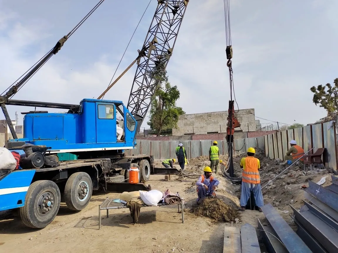 Blue crawler crane and piling rig mobilised at the JICA Faisalabad site with steel and reinforcement laid out